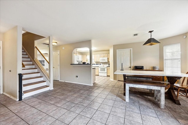 kitchen with hanging light fixtures, white appliances, kitchen peninsula, and light tile patterned floors