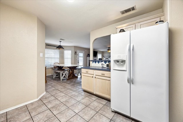 kitchen with pendant lighting, ceiling fan, white refrigerator with ice dispenser, and light tile patterned floors