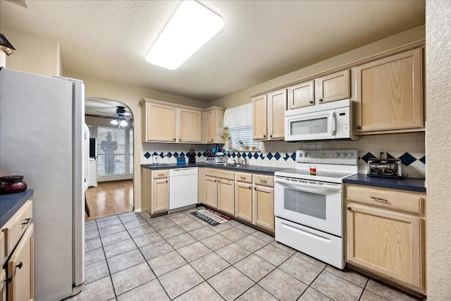 kitchen featuring decorative backsplash, light tile patterned floors, white appliances, and a healthy amount of sunlight