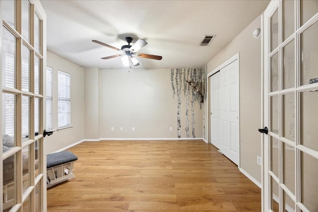 spare room with ceiling fan, light hardwood / wood-style floors, a textured ceiling, and french doors