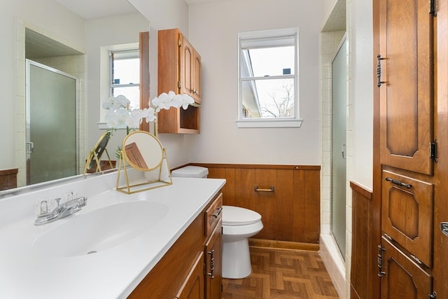 bathroom featuring parquet flooring, vanity, a shower with door, toilet, and wood walls