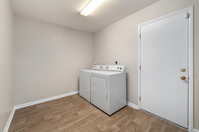 laundry room with washer and clothes dryer, light hardwood / wood-style floors, and a textured ceiling