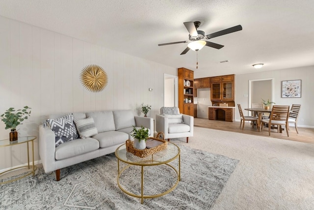 carpeted living room with ceiling fan and a textured ceiling