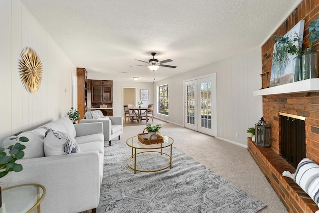 carpeted living room with ceiling fan, a fireplace, a textured ceiling, and wooden walls