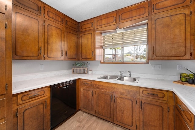 kitchen with a textured ceiling, black dishwasher, light hardwood / wood-style flooring, and sink