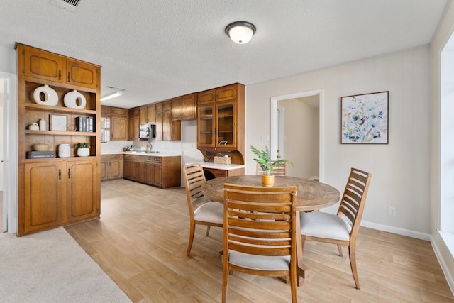 dining area featuring a textured ceiling and light hardwood / wood-style flooring