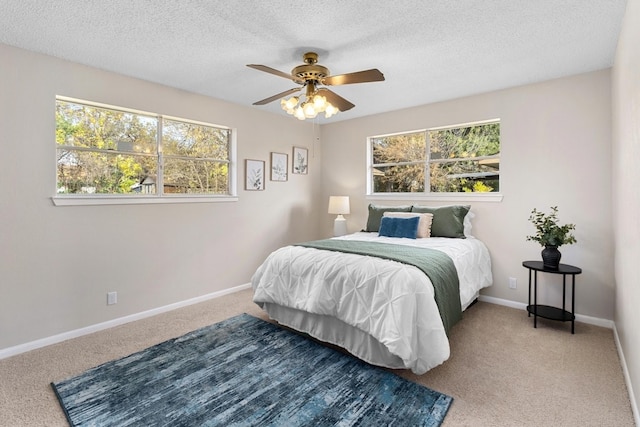 carpeted bedroom featuring a textured ceiling, multiple windows, and ceiling fan