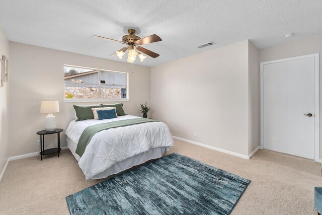 bedroom featuring ceiling fan, light carpet, and a textured ceiling