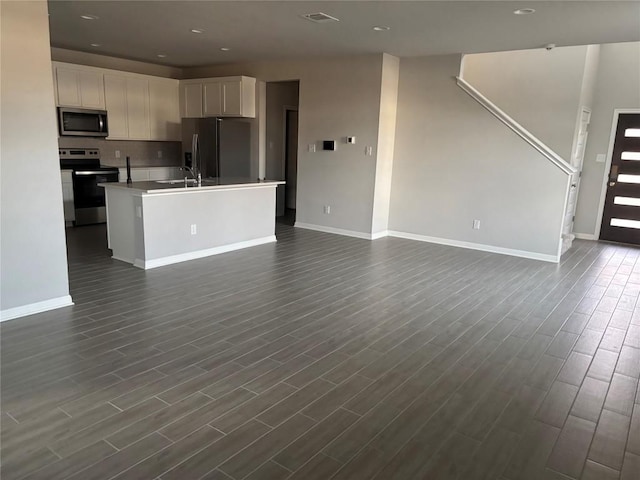 kitchen featuring a center island with sink, sink, dark hardwood / wood-style flooring, white cabinetry, and stainless steel appliances