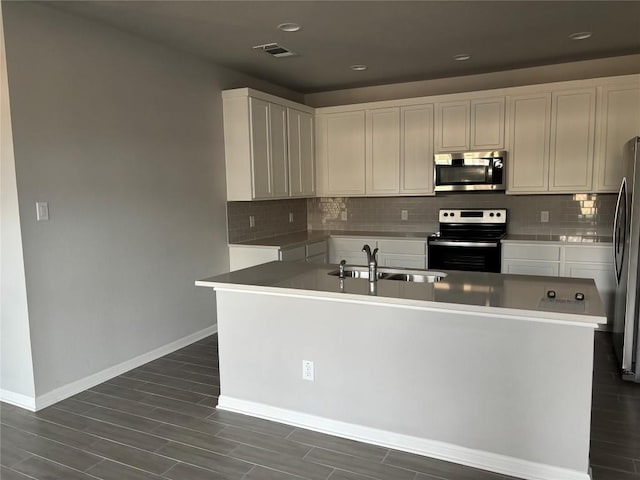 kitchen featuring backsplash, stainless steel appliances, a kitchen island with sink, and sink