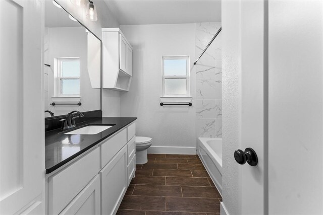 full bathroom featuring tiled shower / bath, vanity, toilet, and a wealth of natural light