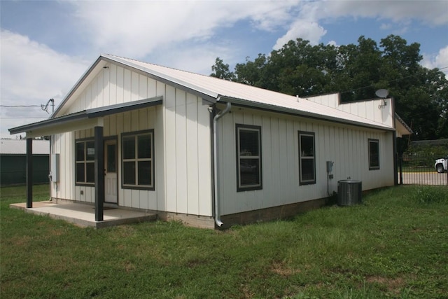 rear view of property with central AC and a lawn