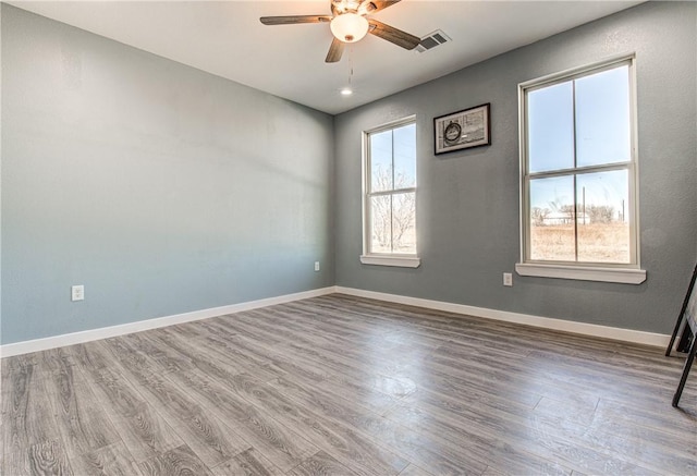 empty room with hardwood / wood-style flooring, ceiling fan, and a healthy amount of sunlight