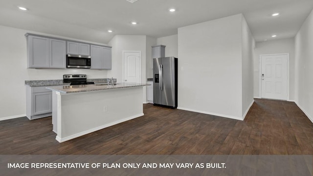 kitchen with a center island with sink, light stone counters, dark wood-type flooring, and appliances with stainless steel finishes