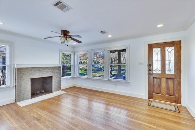 unfurnished living room with ceiling fan, plenty of natural light, crown molding, and a brick fireplace