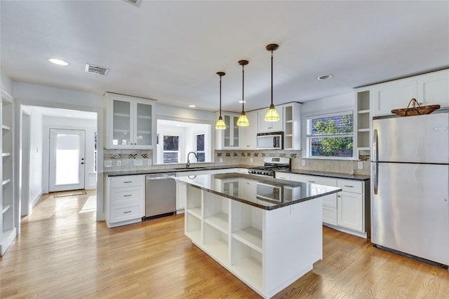 1721 Palma Plz, Austin, TX 78703 - kitchen featuring open shelves, appliances with stainless steel finishes, white cabinetry, backsplash, and a center island