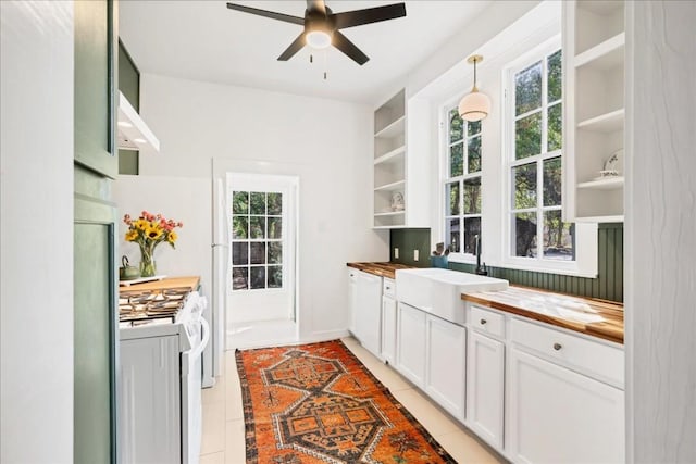 kitchen featuring wood counters, white stove, white cabinets, sink, and ceiling fan