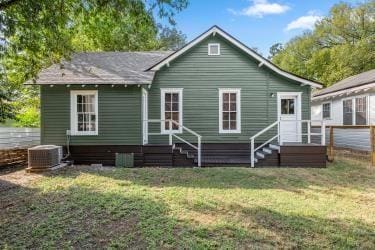 rear view of property with cooling unit and a yard