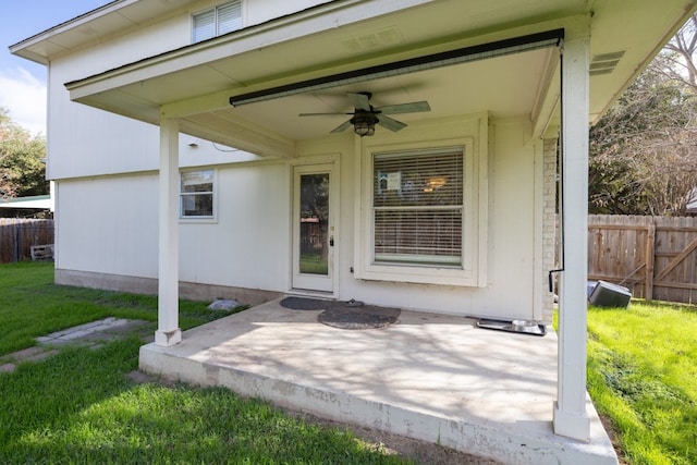 entrance to property featuring a lawn, ceiling fan, and a patio