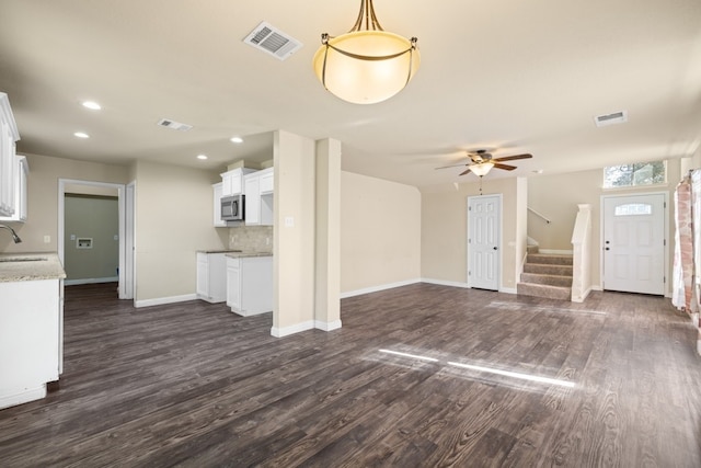 unfurnished living room featuring ceiling fan, sink, and dark wood-type flooring