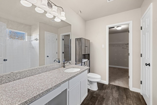 bathroom with a tile shower, toilet, vanity, and hardwood / wood-style flooring