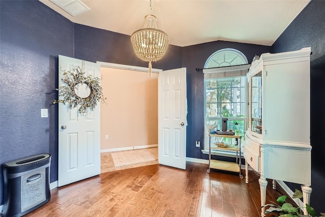 entryway featuring a notable chandelier, lofted ceiling, and wood-type flooring