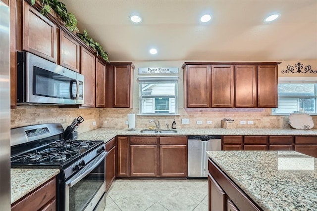 kitchen featuring stainless steel appliances, light stone counters, and sink