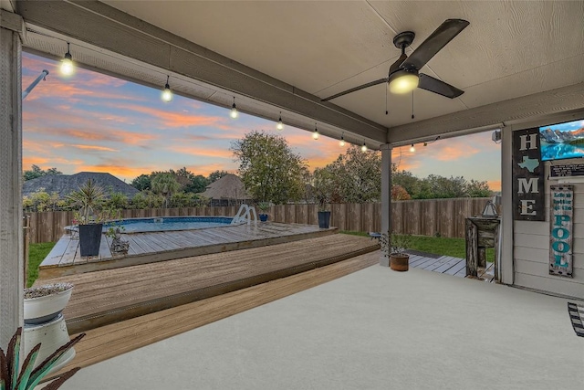 patio terrace at dusk featuring ceiling fan and a pool side deck with mountain view