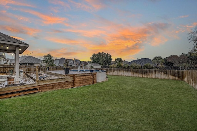 yard at dusk featuring a pool side deck