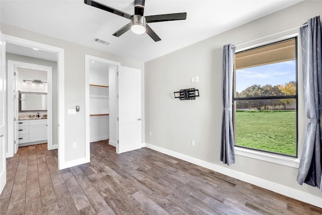 unfurnished bedroom with sink, a spacious closet, a closet, hardwood / wood-style flooring, and ceiling fan