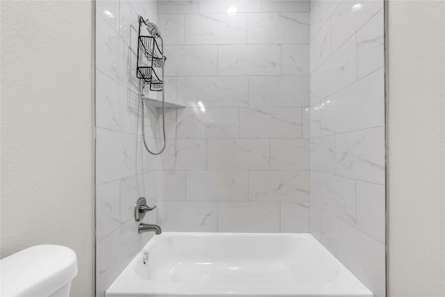 bathroom featuring tiled shower / bath and toilet