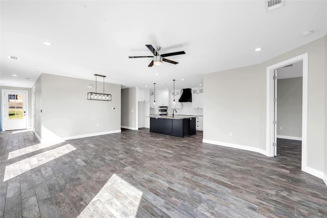 unfurnished living room with ceiling fan, sink, and dark hardwood / wood-style floors