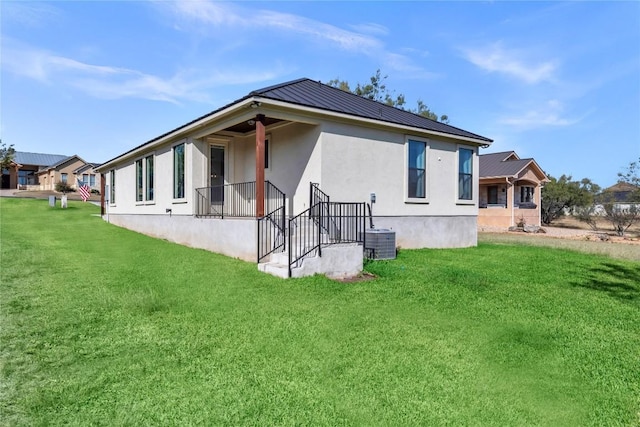 rear view of property with cooling unit and a yard