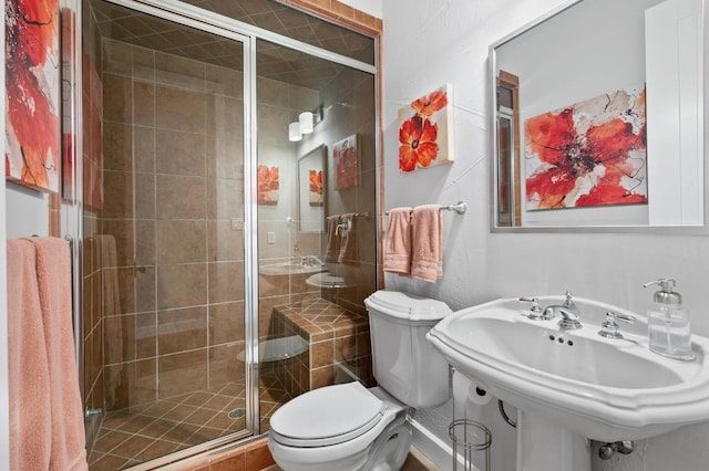 bathroom featuring toilet, a shower with shower door, and sink