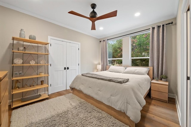 bedroom featuring light wood-type flooring, a closet, ceiling fan, and ornamental molding