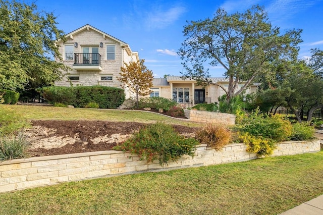 view of front of house with a balcony and a front lawn