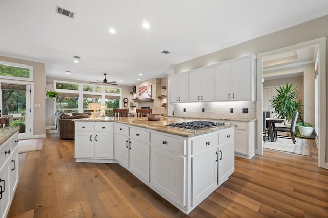 kitchen featuring ceiling fan, light wood-type flooring, white cabinetry, and stainless steel gas cooktop