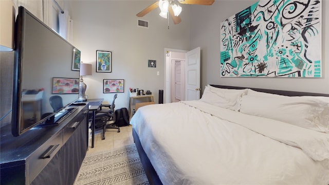 bedroom featuring light tile patterned floors, ceiling fan, and a high ceiling