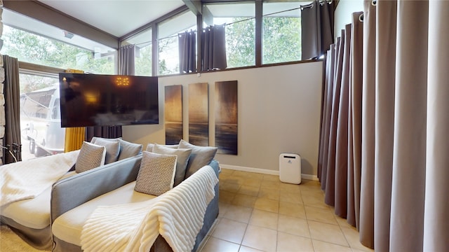 bedroom with a high ceiling, light tile patterned floors, and beam ceiling