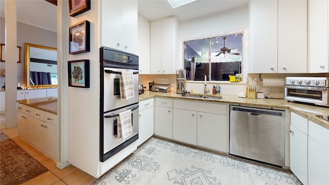 kitchen featuring sink, light tile patterned floors, white cabinetry, stainless steel appliances, and light stone counters