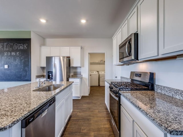 kitchen with stainless steel appliances, washer and clothes dryer, sink, dark hardwood / wood-style floors, and white cabinetry