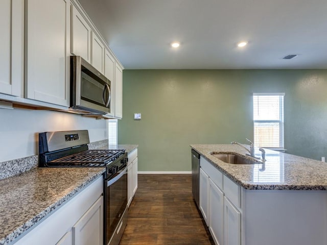 kitchen featuring white cabinets, sink, an island with sink, dark hardwood / wood-style flooring, and stainless steel appliances