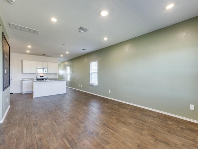 kitchen featuring wood-type flooring, stainless steel appliances, white cabinetry, and a kitchen island