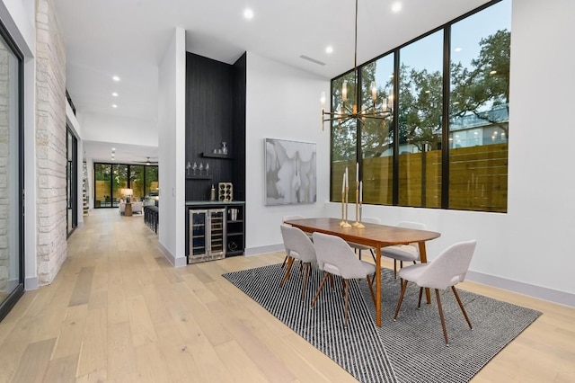 dining area with a chandelier, bar area, and light hardwood / wood-style flooring