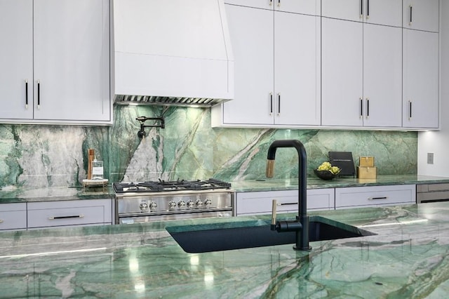 kitchen featuring white cabinets, decorative backsplash, stainless steel range oven, and stone counters