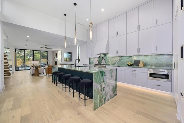 2423 S 5th St, Austin, TX 78704 - kitchen with premium range hood, light wood-type flooring, decorative backsplash, a center island with sink, and recessed lighting