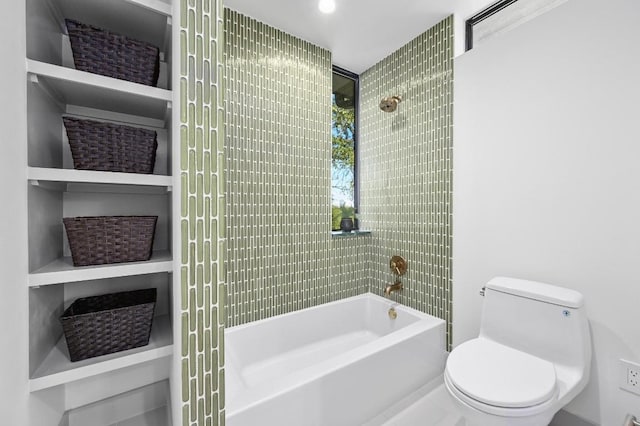 bathroom featuring tiled shower / bath combo and toilet