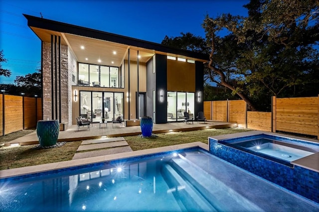 rear view of property featuring a swimming pool with hot tub and a patio