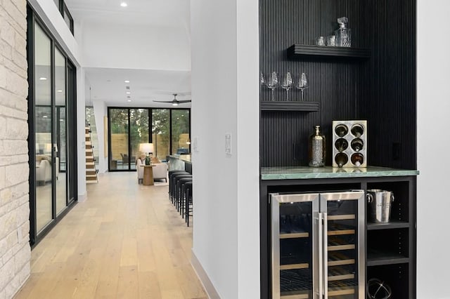 bar with ceiling fan, a wall of windows, wood-type flooring, and wine cooler