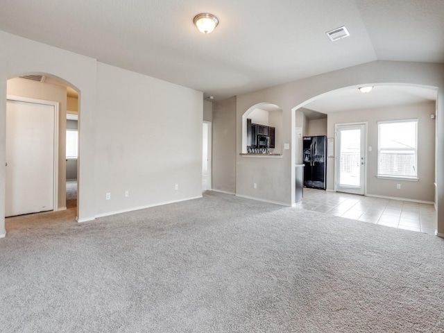 unfurnished living room featuring light carpet and vaulted ceiling